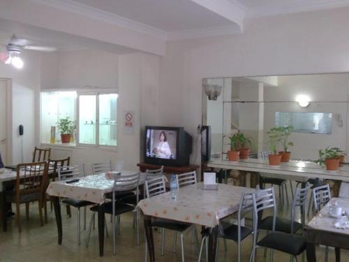 a dining room with tables and chairs and a tv at Real Splendid Hotel in Buenos Aires