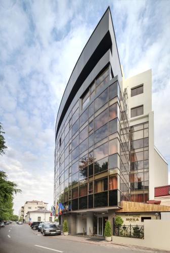 a tall building with glass windows on a street at MOXA Bucharest Boutique Hotel in Bucharest