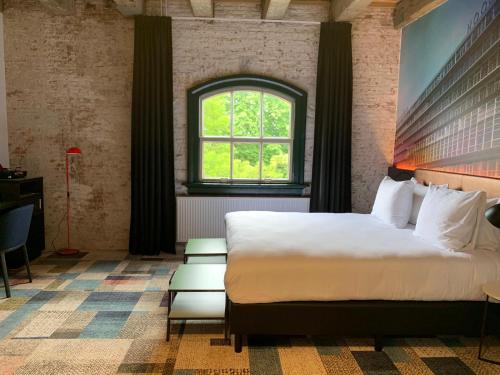 a bedroom with a large bed and a window at Onderwijshotel De Rooi Pannen Breda in Breda