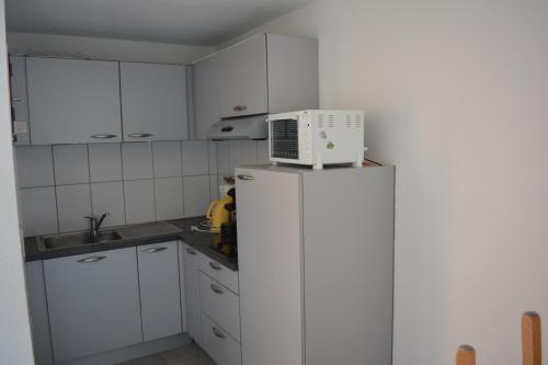 Il comprend une cuisine blanche équipée d'un four micro-ondes et d'un réfrigérateur. dans l'établissement Vue mer et plages à pied, à Sète