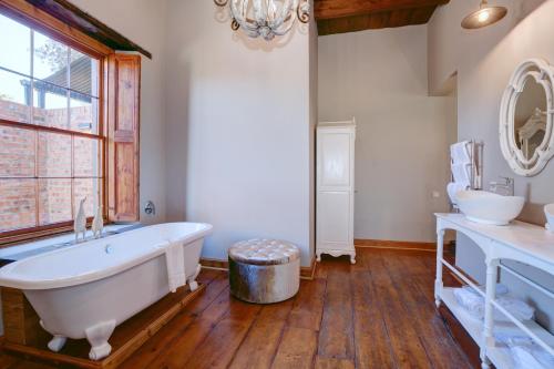 La salle de bains est pourvue d'une grande baignoire et de 2 lavabos. dans l'établissement Botlierskop The Village Lodge, à Groot Brakrivier
