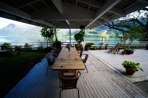 a wooden table and chairs on a deck with a view of a lake at Fjord House in Grimo
