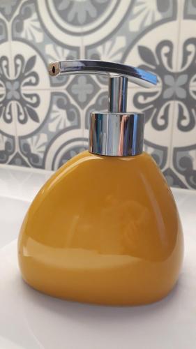 a yellow toothbrush holder sitting in a bathroom at Une Parenthèse en Champagne in Jaucourt