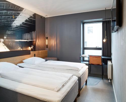 a hotel room with three beds and a desk at Zleep Hotel Aalborg in Aalborg