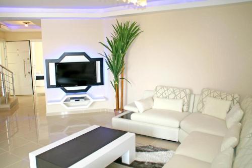 شقق بيليك غولف فيليدج في بيليك: غرفة معيشة مع أريكة بيضاء وتلفزيون