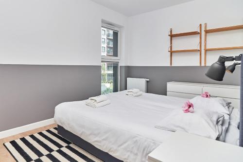 a bedroom with two beds with white sheets and pink flowers at Apartments Wrocław Małopanewska in Wrocław