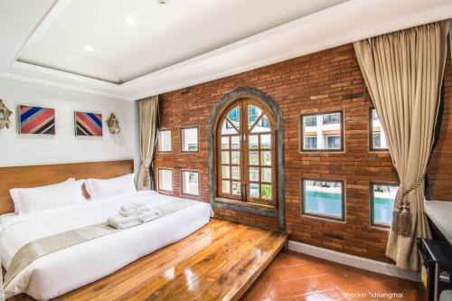 a bedroom with a large bed and a brick wall at Lanna Oriental Hotel in Chiang Mai