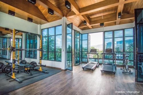 a gym with gym equipment and glass windows at Lanna Oriental Hotel in Chiang Mai