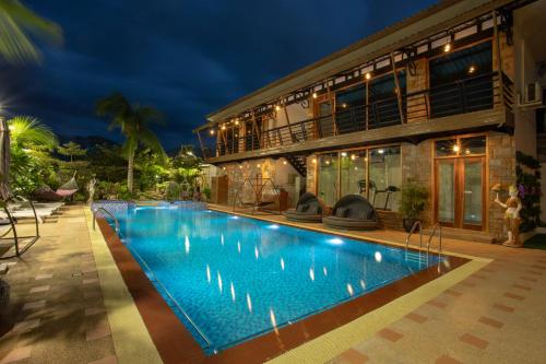 a villa with a swimming pool at night at Mandalay Lodge Hotel in Mandalay
