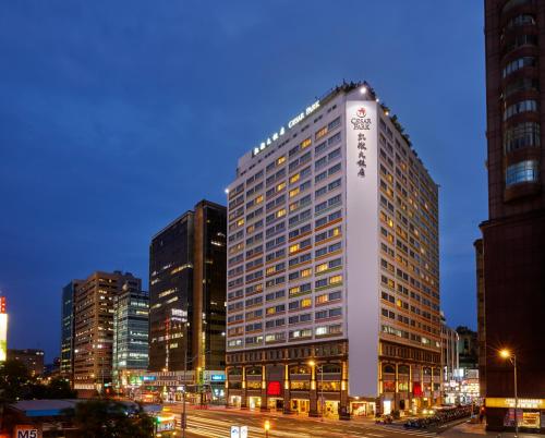 台北的住宿－台北凱撒大飯店，夜晚在城市里高大的白色建筑