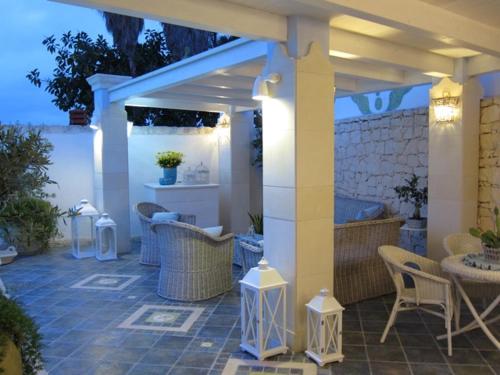 an outdoor patio with wicker chairs and tables and areens at Villa Antares in Siracusa