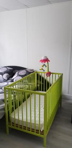 a green crib in a room with a bed at 84 ėme rue in Vitry-sur-Seine
