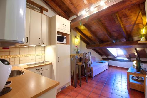 cocina con armarios blancos y techo de madera en La Buhardilla de Andrea, en Cuenca