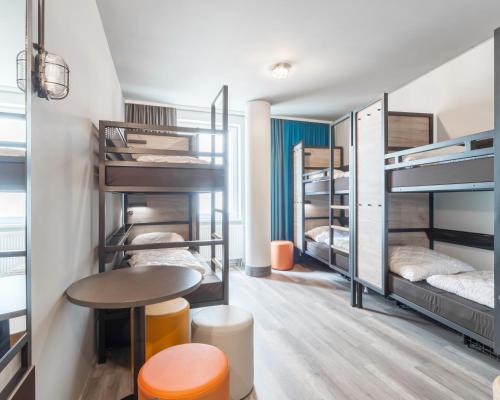 a room with bunk beds and a table and stool at a&o Frankfurt Galluswarte in Frankfurt/Main
