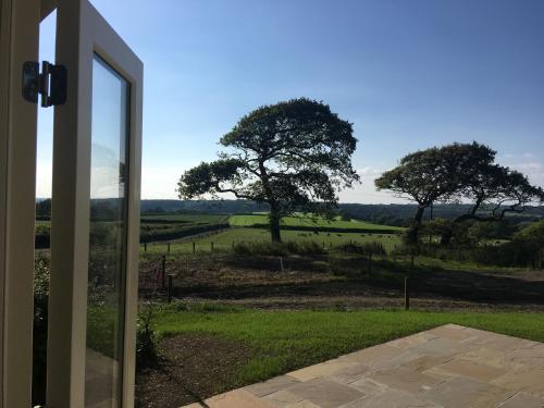 a sliding glass door with a view of a tree at Broomhill Barns in Minwear
