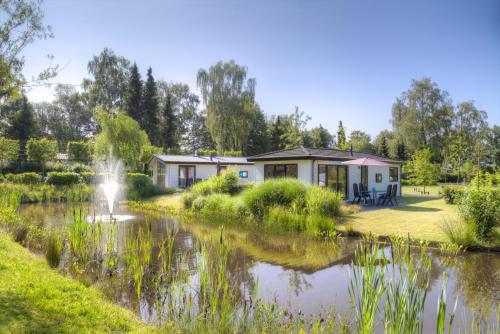a house next to a pond with a fountain at Recreatiepark de Wielerbaan in Wageningen