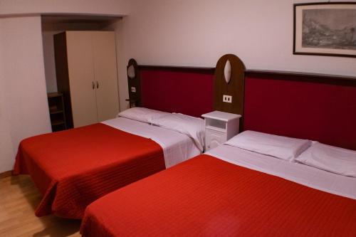 two beds in a room with red and white at Residence Al Lago in Castiglione del Lago