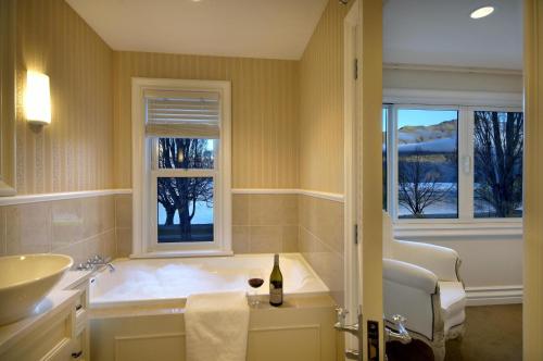 a bathroom with a tub and a sink and two windows at Esplanade Queenstown by Staysouth in Queenstown