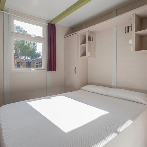 a bedroom with a large bed and a window at HolaCamp Sitges Garrofer in Sitges