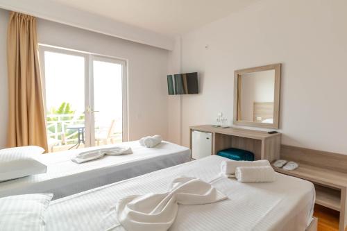 a hotel room with two beds and a mirror at Sun N Blue Hotel in Sarandë