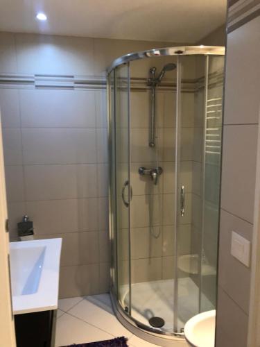 une douche en verre dans une salle de bain avec un lavabo dans l'établissement West bay, à Menton