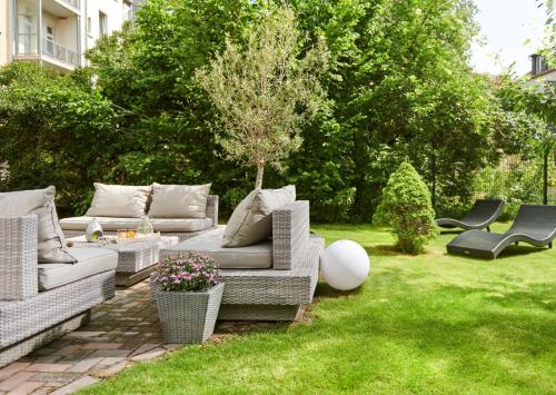 a garden with couches and chairs in the grass at Auenwald Hotel und Apartmenthaus in Leipzig