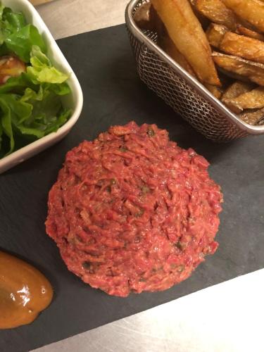 a hamburger patty next to a bowl of fries and a salad at Logis Hôtel l'Abricotine in Tain-lʼHermitage