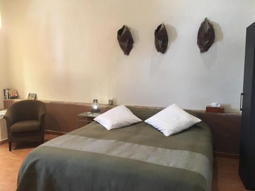 a bedroom with a bed with two pillows and a chair at Darcilla Guest House in Tarifa