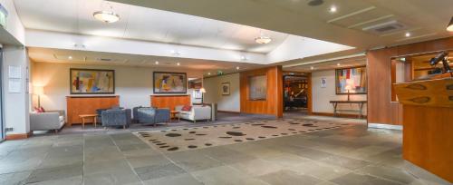 a lobby with a waiting area with chairs and tables at Apollo Hotel in Basingstoke