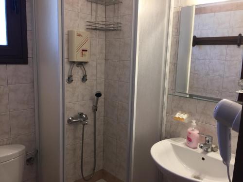 een badkamer met een douche, een toilet en een wastafel bij Vervekis Apartments in Mesovoúnia