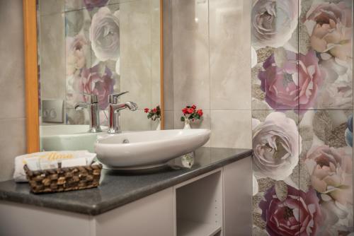 a bathroom with a sink and a mirror and flowers at Alma Hotel in Petra