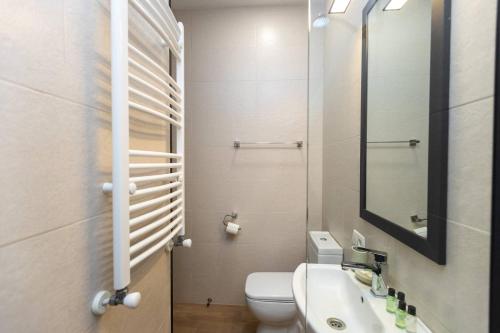 y baño con aseo, lavabo y espejo. en Wehost Apartment With 3 Bedrooms, en Tiflis