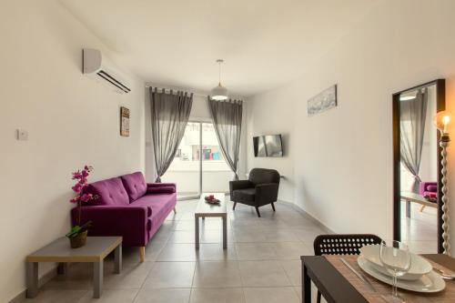 a living room with a purple couch and a table at Andriana City Centre Flat in Larnaka