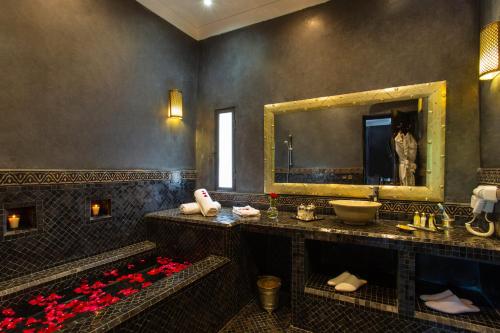 baño con lavabo, espejo y flores rojas en Riad Jawad & Spa, en Marrakech