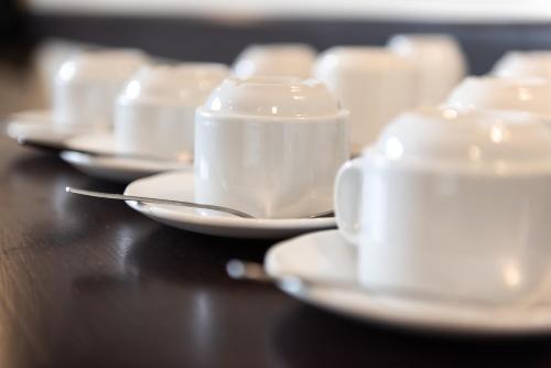 a group of white cups and saucers on a table at Dragonfly Hotel Bury St Edmunds in Bury Saint Edmunds