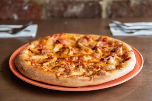 a pizza on an orange plate on a table at Dragonfly Hotel Bury St Edmunds in Bury Saint Edmunds