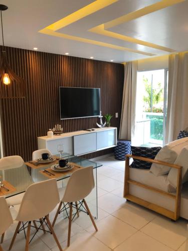a living room with a tv and a table and chairs at Palm Acqua Resort in Porto De Galinhas