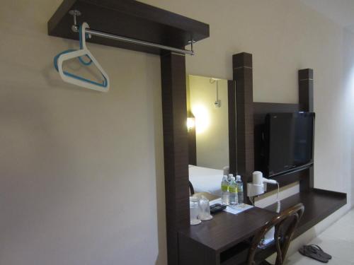 een kamer met een bureau, een televisie en een spiegel bij Radiant Hotel in Sitiawan