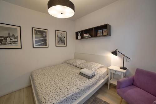 a bedroom with a bed and a purple chair at Apartament LAVENDER in Śrem