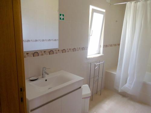 a bathroom with a sink and a toilet and a window at Casa Amarela in Pêra