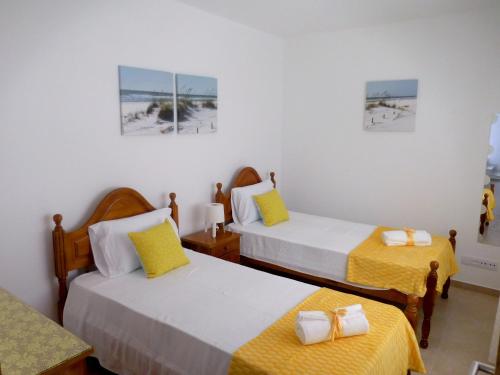 a room with two beds with yellow sheets at Casa Amarela in Pêra