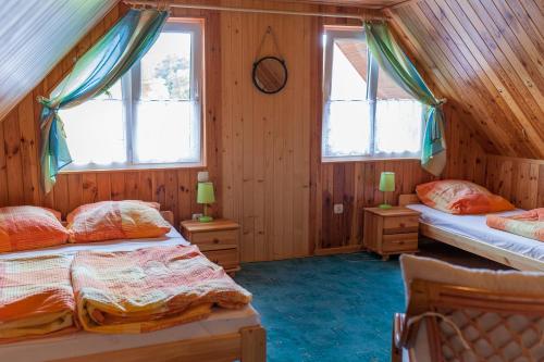 two beds in a room with wooden walls and windows at Domek we Władku in Władysławowo