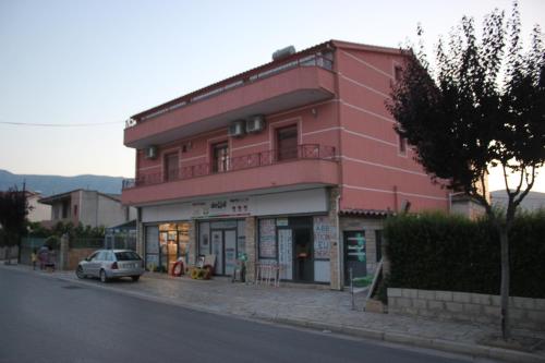a pink building with a car parked in front of it at Guesthouse Leo in Berat