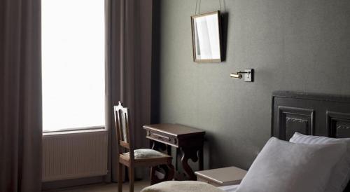 a bedroom with a desk and a bed and a chair at Boutique hotel Sint Jacob in Maastricht