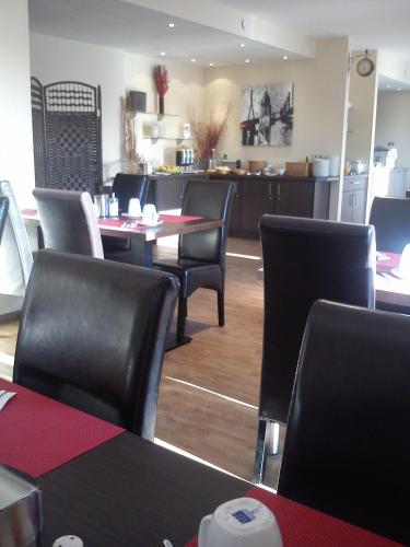 a restaurant with black chairs and a table and a kitchen at Arena Hotel in Henstedt-Ulzburg