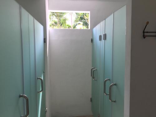 a row of blue stalls in a bathroom with a window at Mangga Wangga Living in Uluwatu