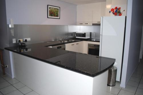 a kitchen with white cabinets and white appliances at Surfside On The Beach in Buddina