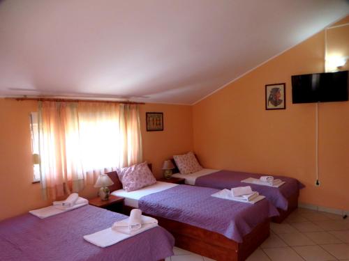 a hotel room with two beds and a flat screen tv at Guest House Villa Živanović in Herceg-Novi