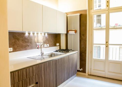 d'une cuisine avec des placards blancs, un évier et une fenêtre. dans l'établissement LuxRent Apartment Castello, à Turin