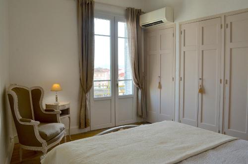 a bedroom with a bed and a chair and a window at 2 Pièces Liberté Plein Centre in Saint-Raphaël